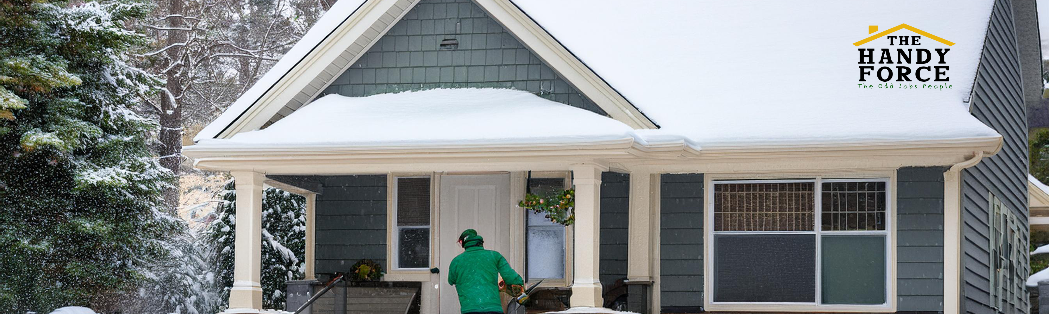 A cozy winter home with a snow-covered roof and clear, clean gutters. The house's windows are warmly lit from inside, with visible caulking and weatherstripping sealing the edges. A worker wearing a dark green polo shirt (representing The HandyForce) is seen inspecting or working on a doorframe, sealing cracks. The foreground includes insulated pipes and a snow shovel resting on the porch, symbolizing winter preparation. The scene should evoke comfort, safety, and readiness for cold weather.