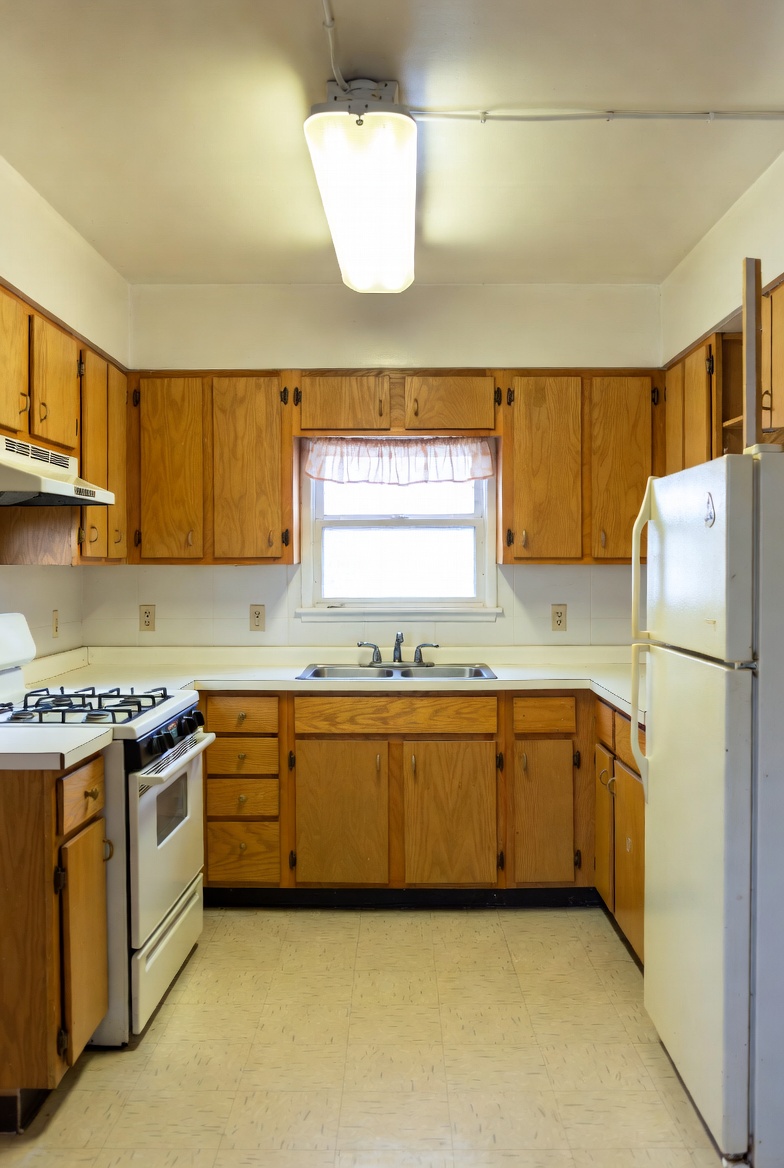 Dated 1960s oak cabinet kitchen with fluorescent lighting and vinyl floor before HandyForce kitchen renovation in East York Toronto